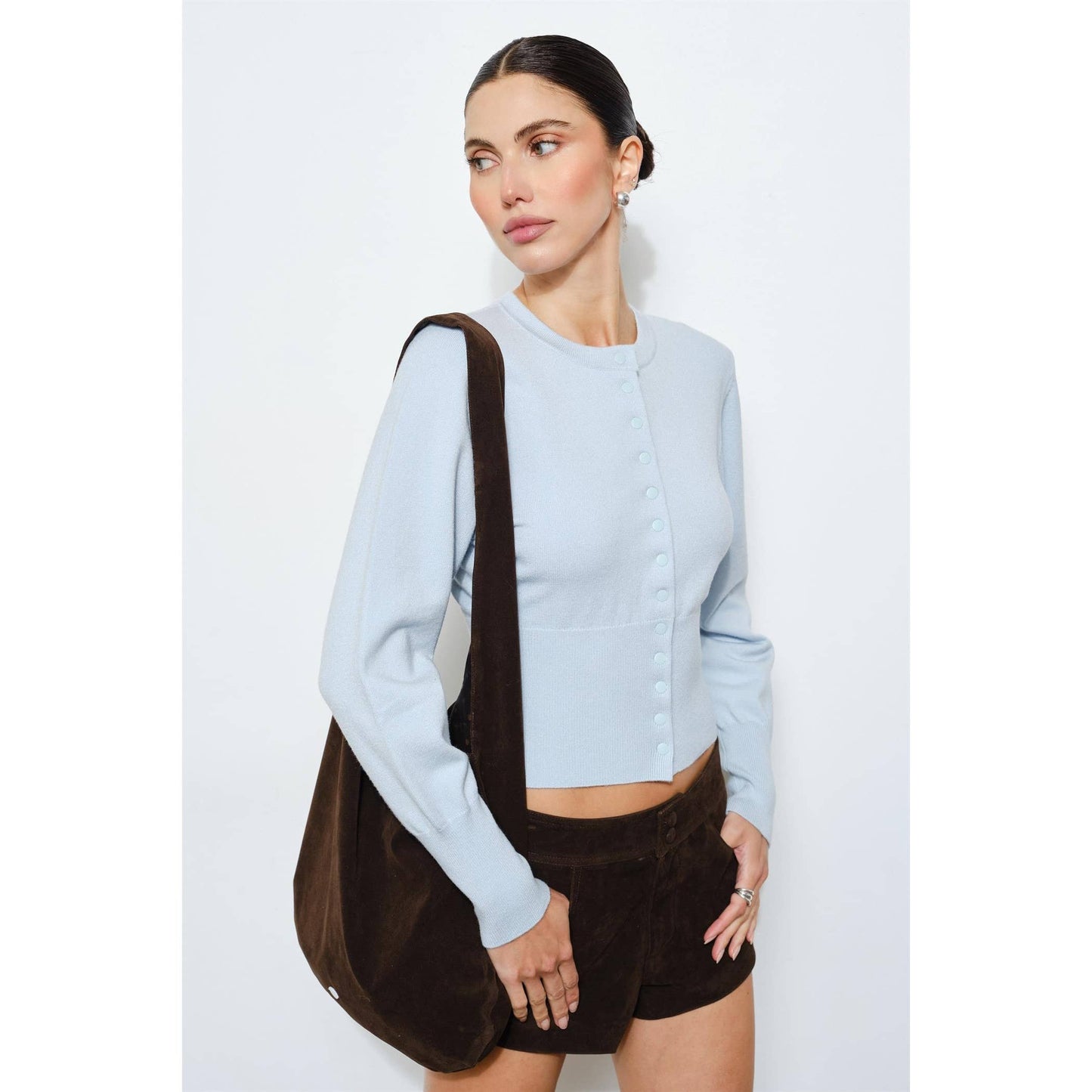 Light blue cropped cardigan with button details, paired with brown corduroy shorts and a matching bag.