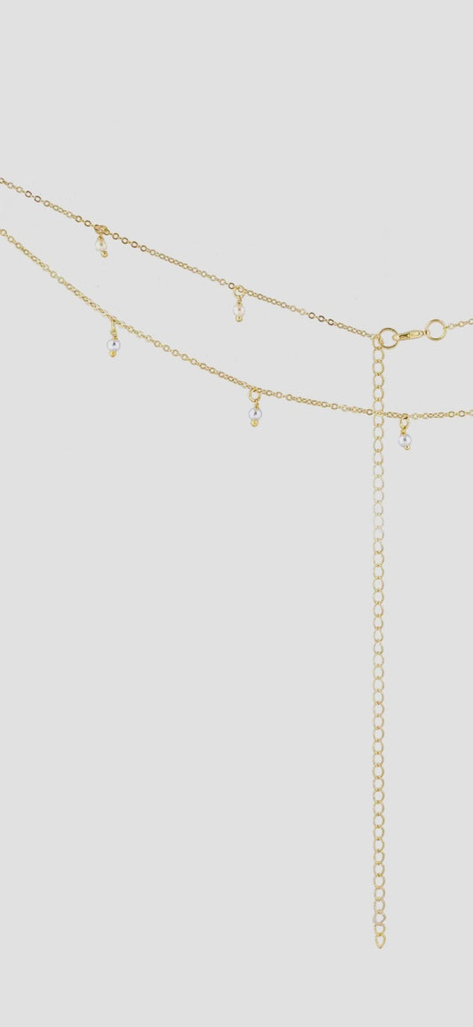 Gold belly chain with small beads on a light gray background
