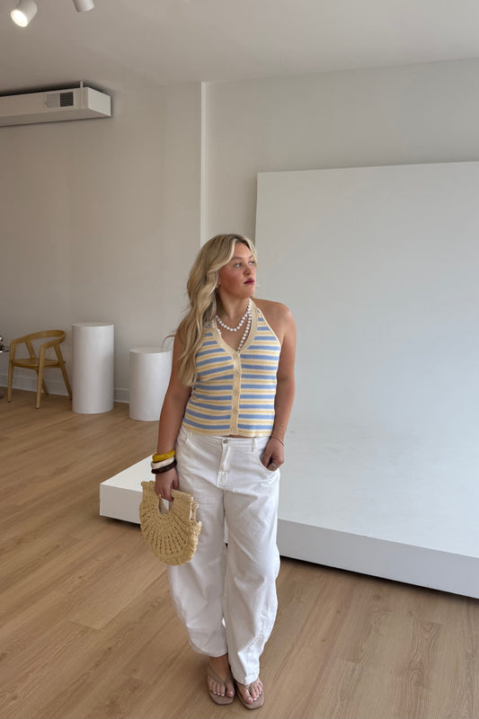 Woman in a striped top and white pants standing in a minimalistic room.