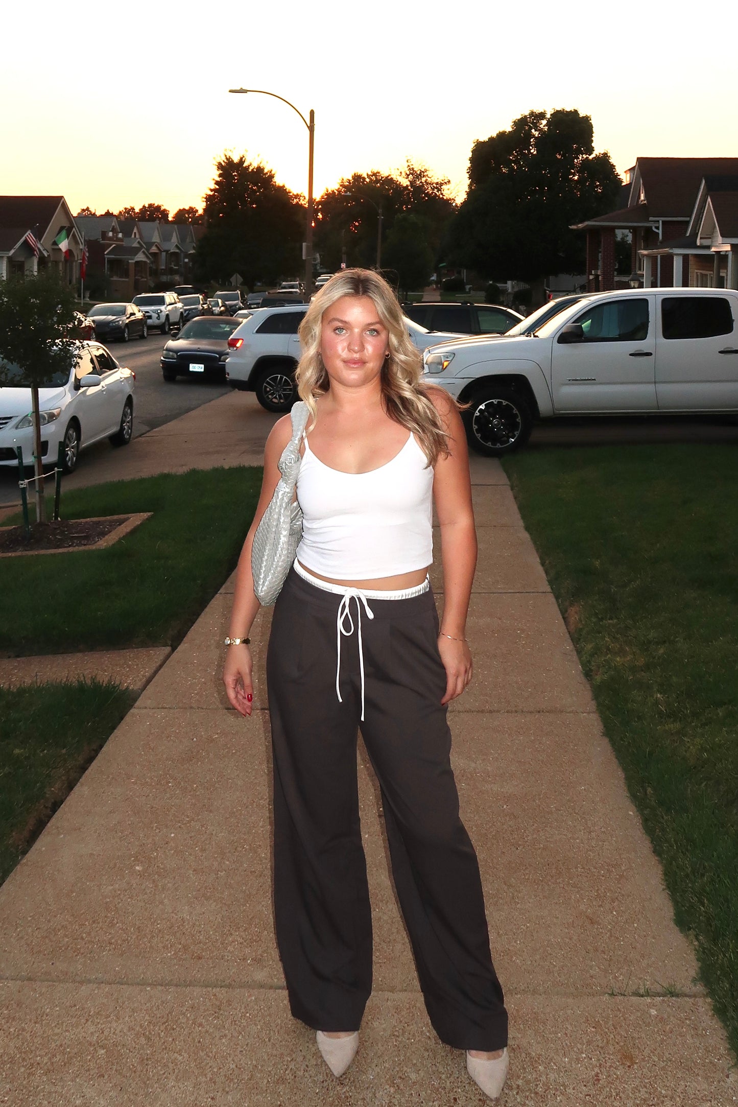Casual summer outfit: white crop top and gray wide-leg pants, stylishly paired with a silver bag.