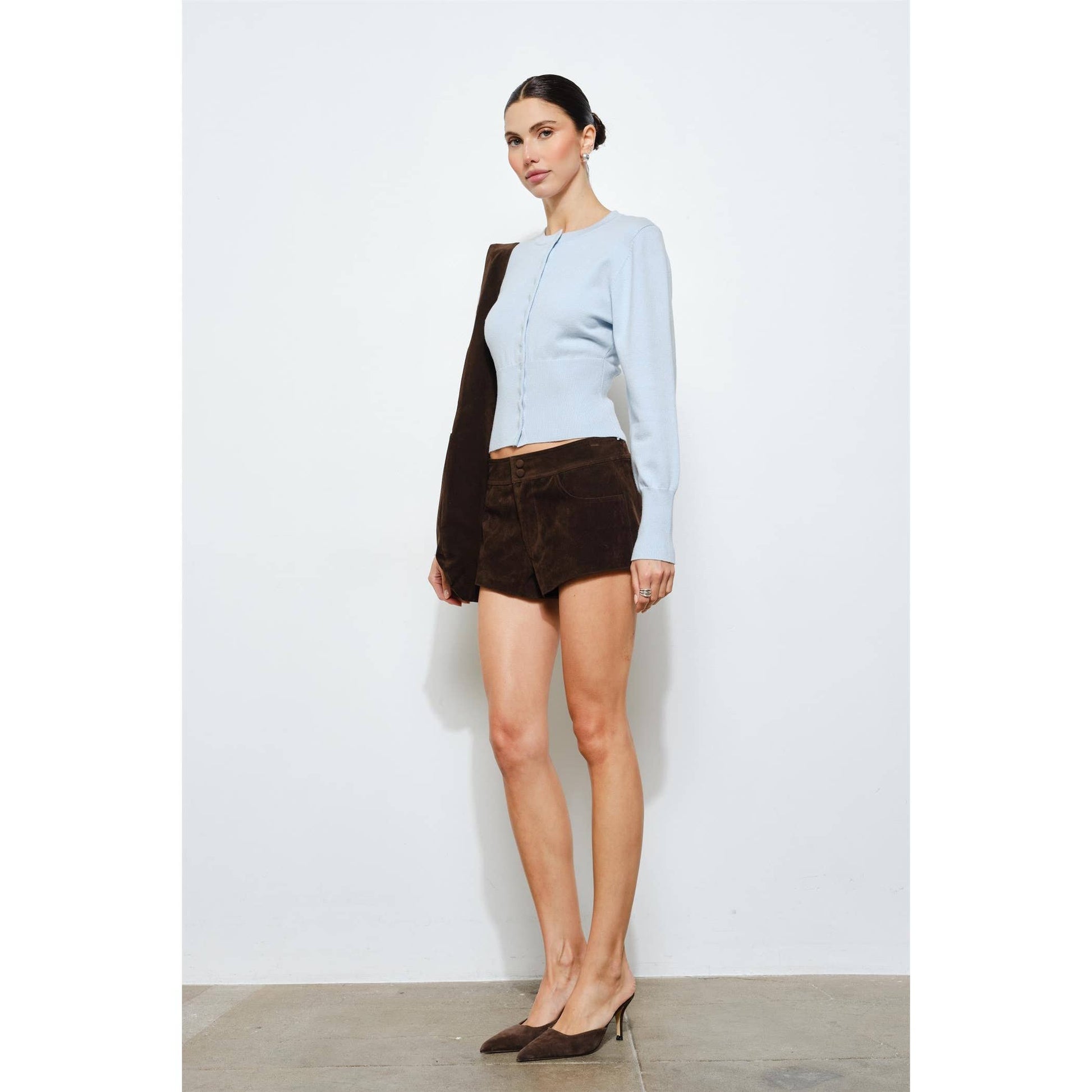 Light blue knitted cardigan with brown suede shorts and matching heels, perfect for stylish casual wear.