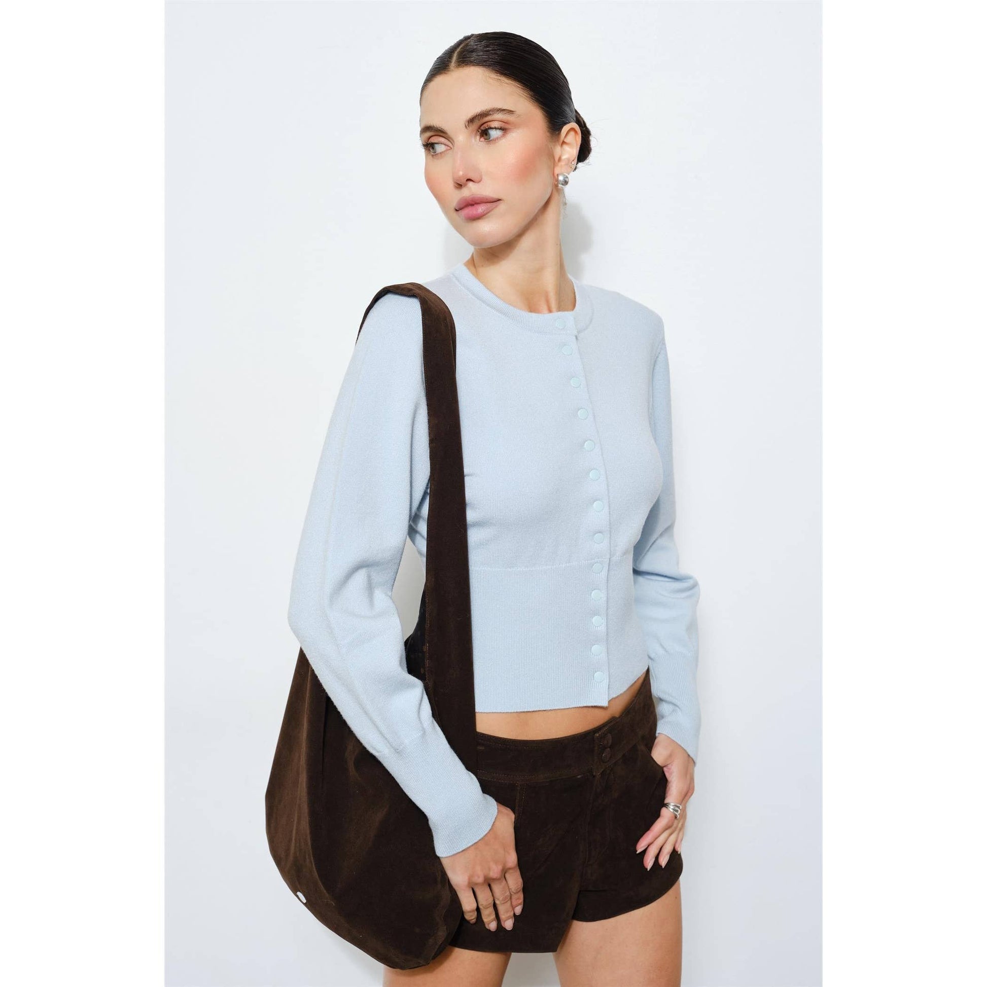 Light blue cropped cardigan with button details, paired with brown corduroy shorts and a matching bag.