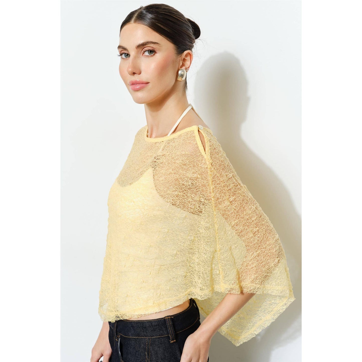 Woman wearing a yellow lace shawl against a white background