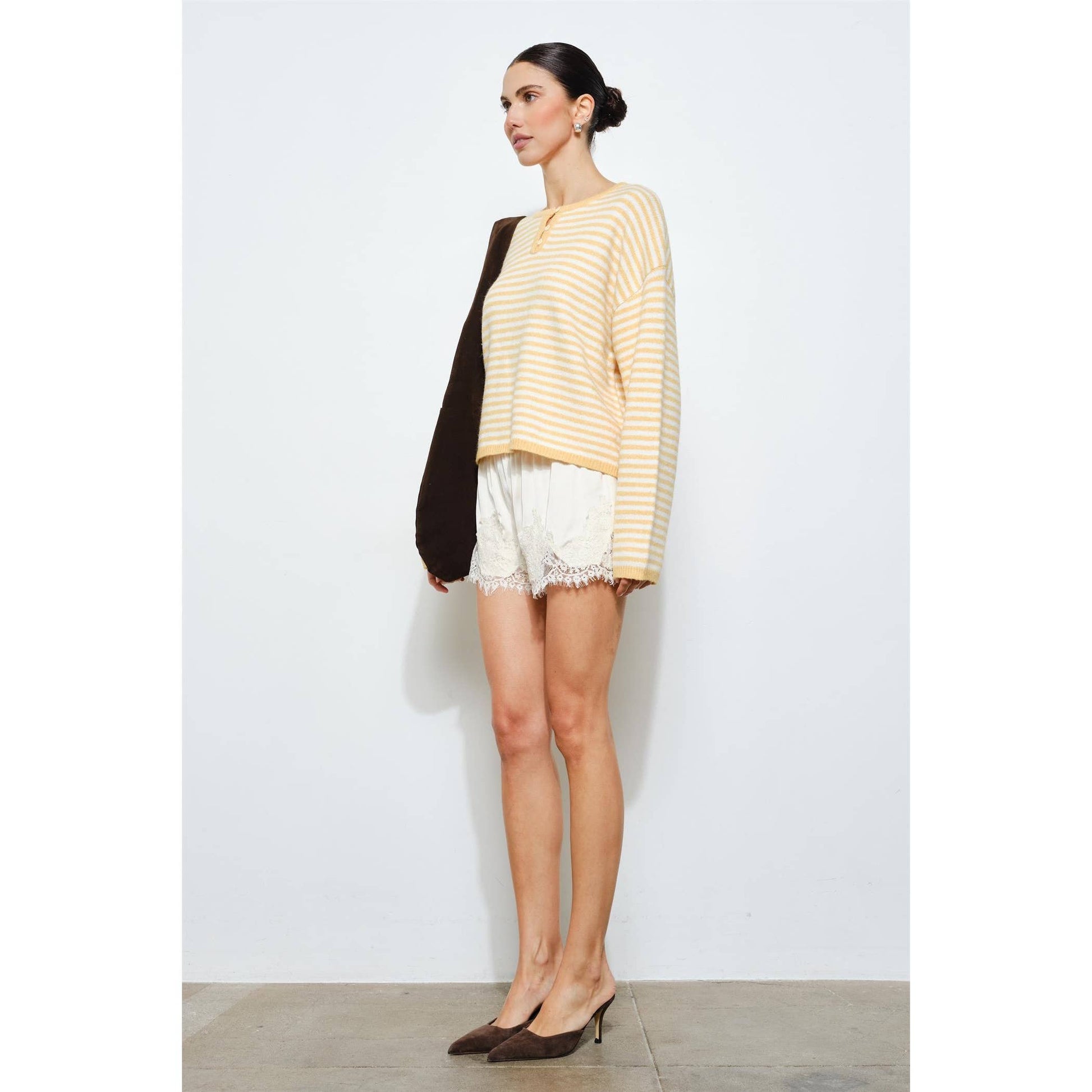 Woman wearing a striped sweater and shorts against a white background