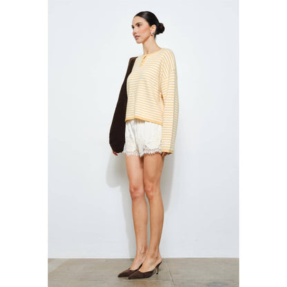 Woman wearing a striped sweater and shorts against a white background