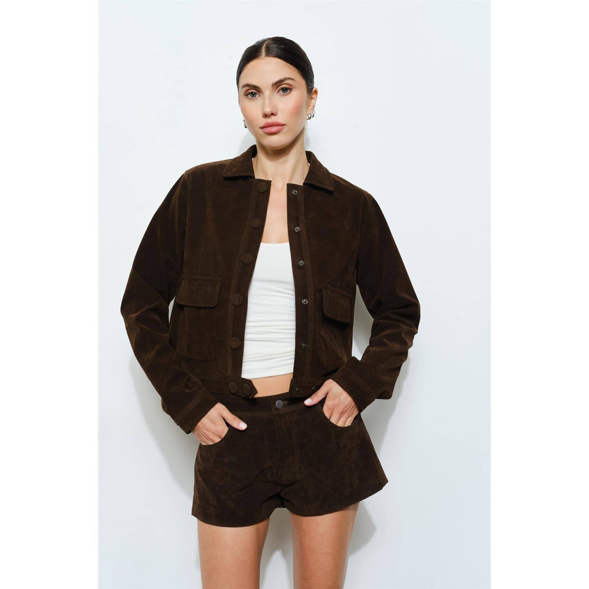 Brown suede cropped jacket with button closure and patch pockets, styled with matching shorts.