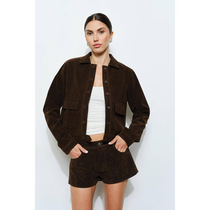 Brown suede cropped jacket with button closure and patch pockets, styled with matching shorts.
