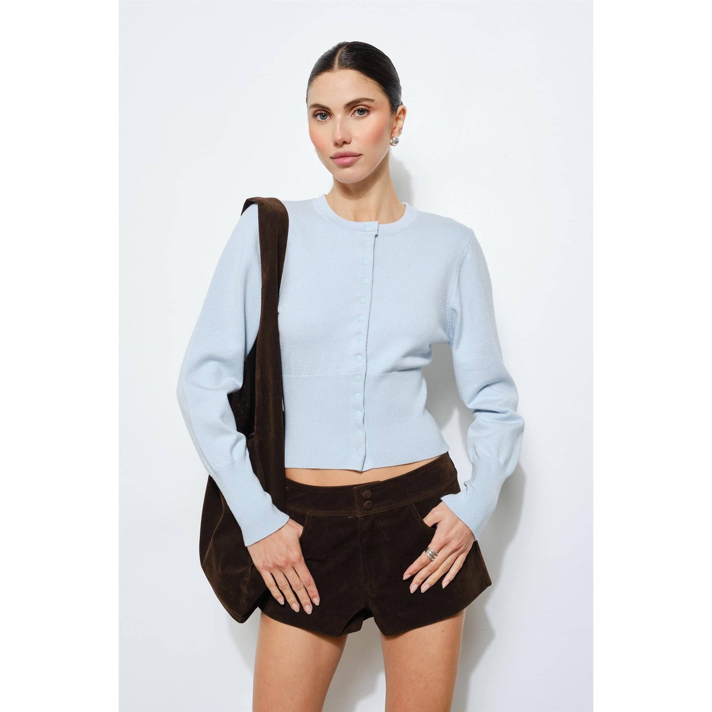 Light blue cropped cardigan with button closure, paired with brown suede shorts.