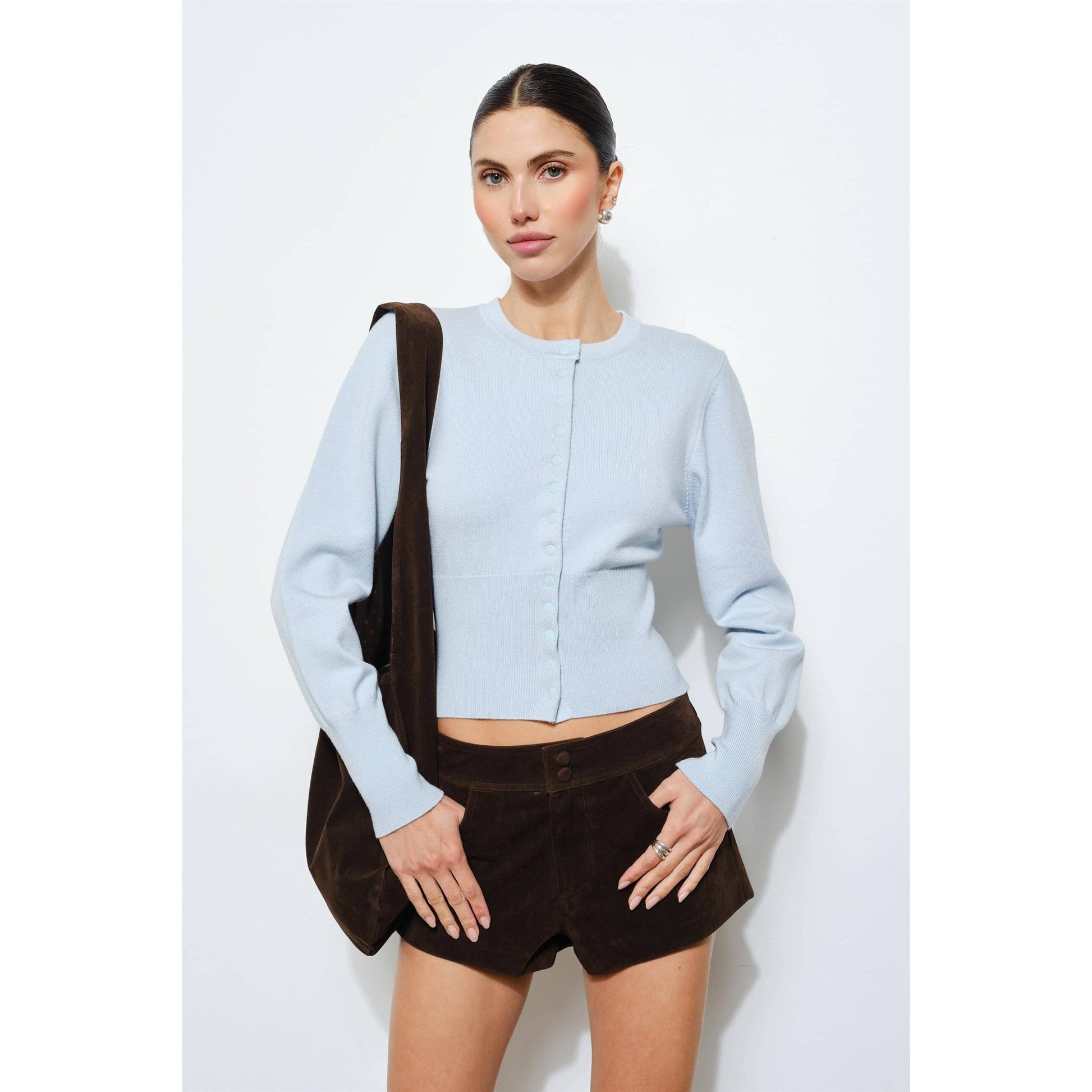 Light blue cropped cardigan with button closure, paired with brown suede shorts.