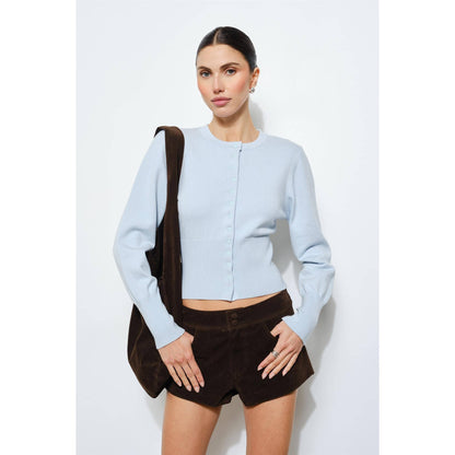 Light blue cropped cardigan with button closure, paired with brown suede shorts.
