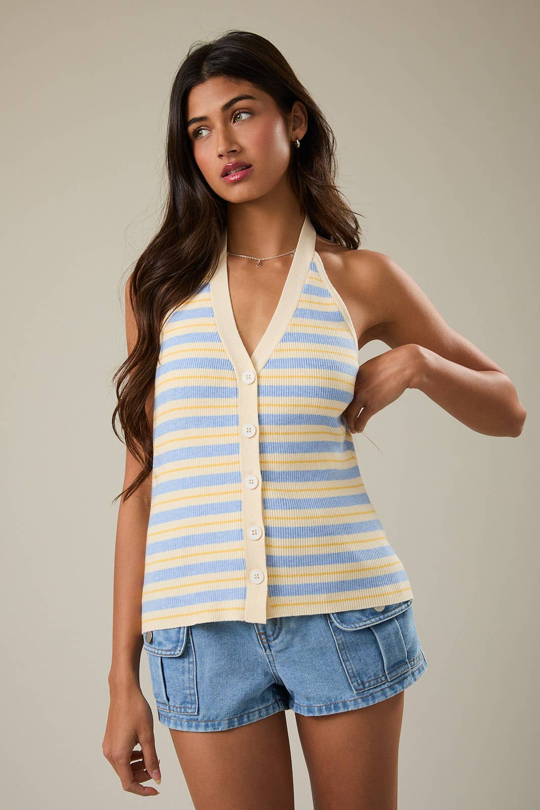 Woman wearing a striped halter top and denim shorts against a neutral background