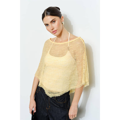 Woman wearing a yellow lace top against a white background