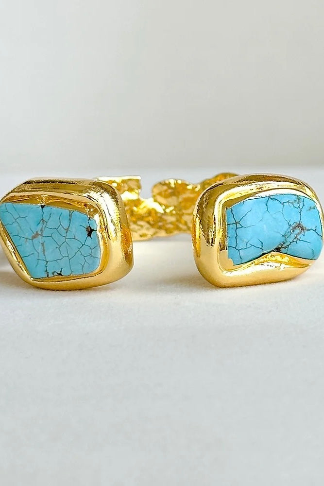 A gold-plated cuff bracelet featuring turquoise semi-precious stones.