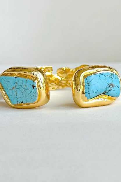 A gold-plated cuff bracelet featuring turquoise semi-precious stones.