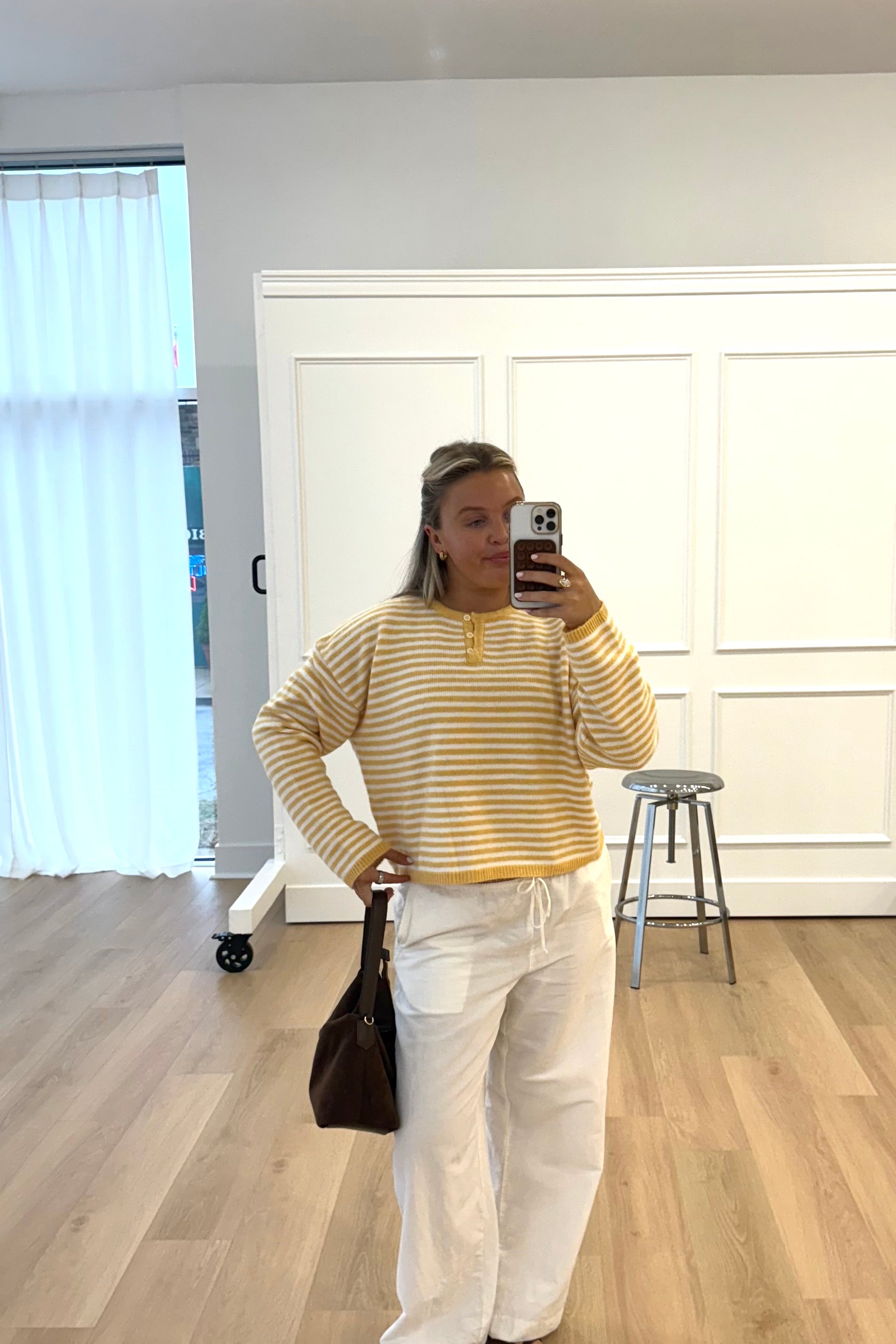 Cozy yellow and white striped sweater, perfect for casual looks, paired with lightweight white pants.
