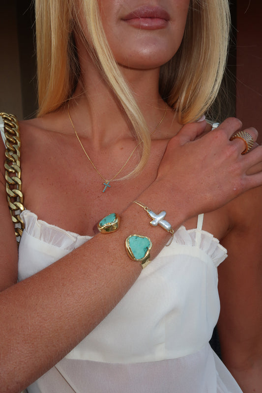 Close-up of a person's arm with multiple bracelets and a ring, wearing a white top.