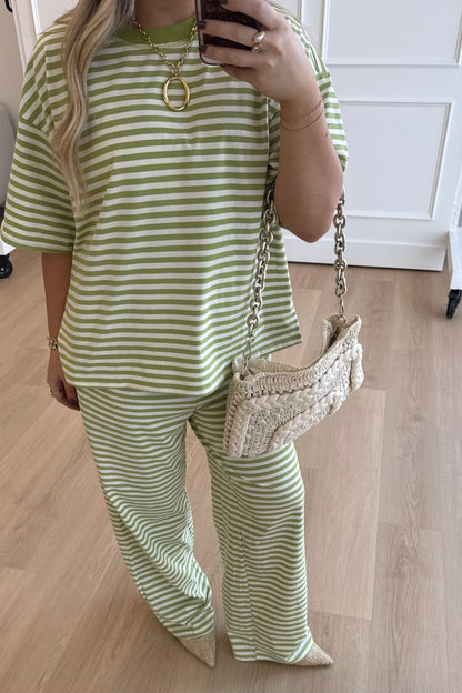 Person wearing a green and white striped outfit with a textured handbag indoors.