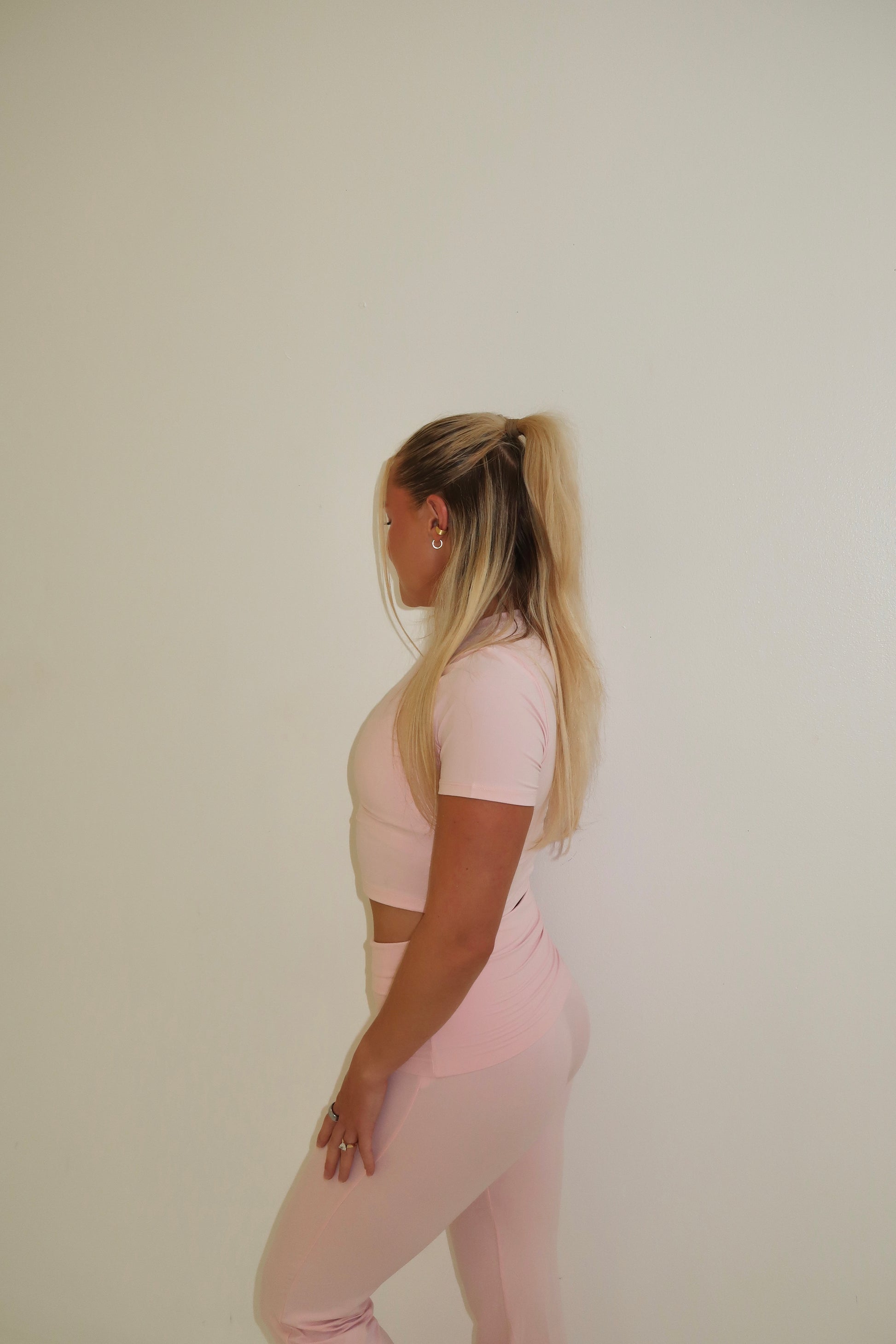 Person wearing a pink outfit standing against a plain background