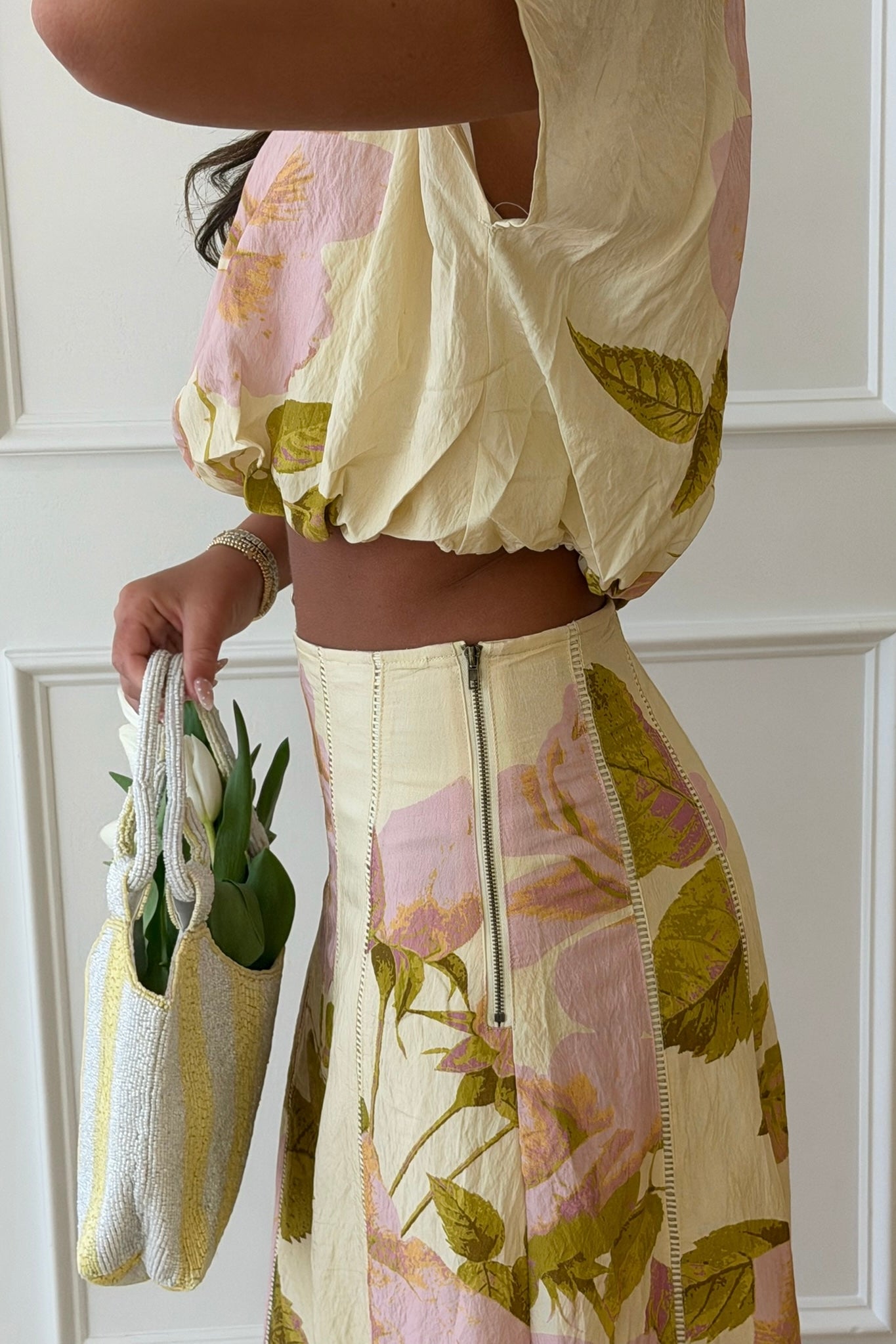 Person wearing a floral dress holding a matching bag against a white background