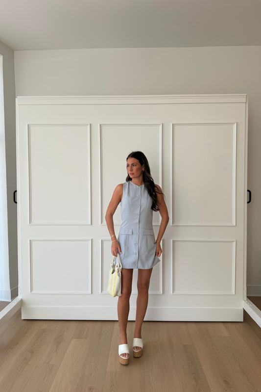 Woman standing in a room with white paneled walls and wooden flooring.