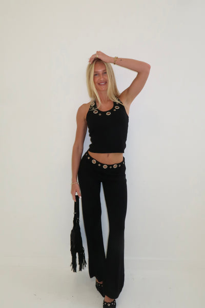 Stylish women's black crop top and flared pants set with circular accents, perfect for casual outings.