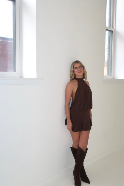 Chic brown halter mini dress with flared hem, styled with knee-high brown boots.