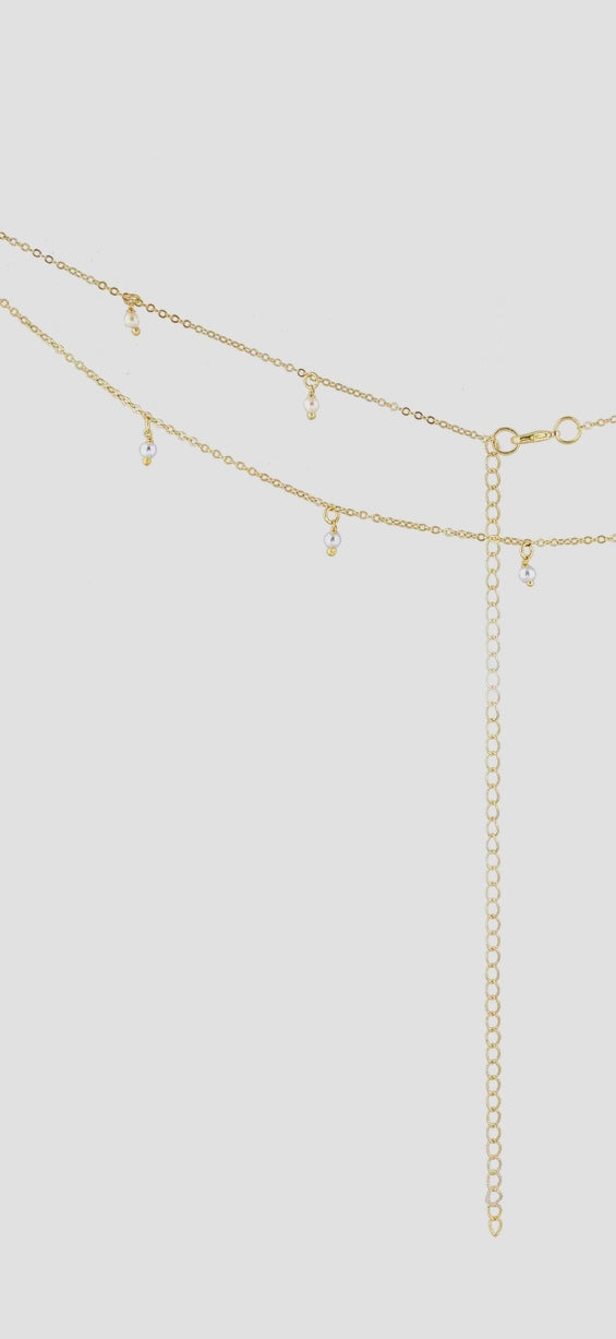 Gold belly chain with small beads on a light gray background