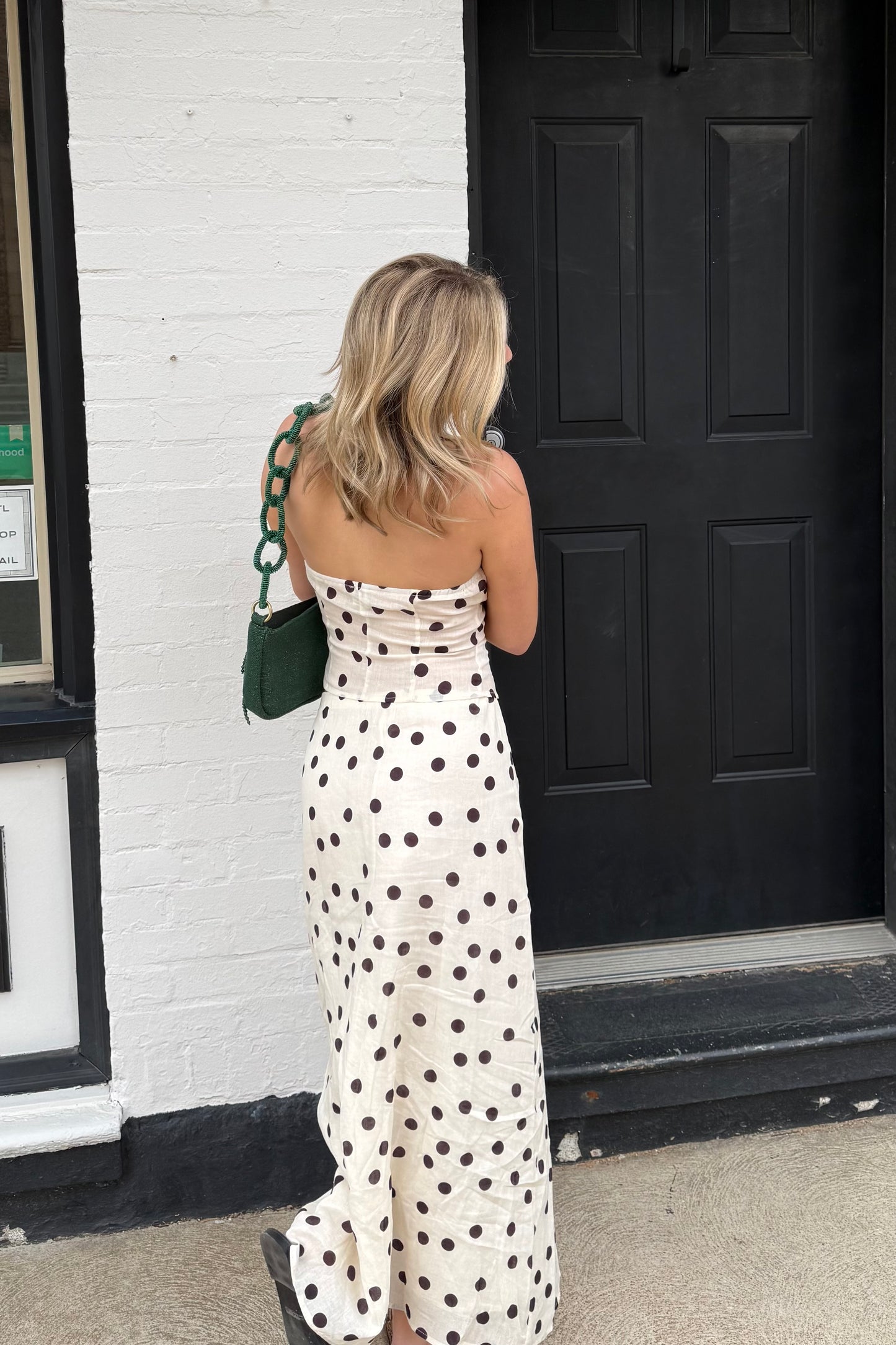 Woman in a polka dot dress standing in front of a black door.