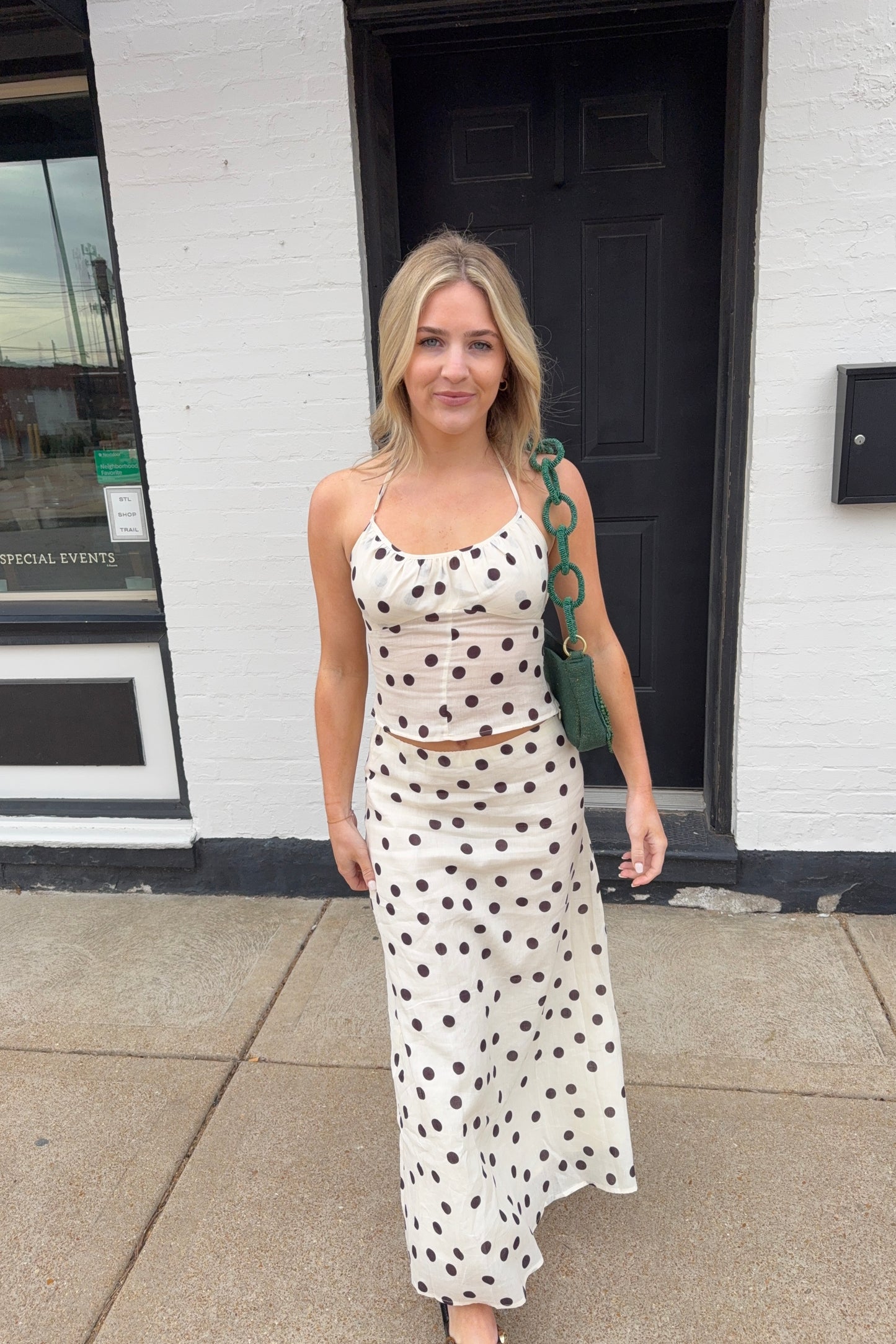 Woman in a polka dot dress standing outside a building