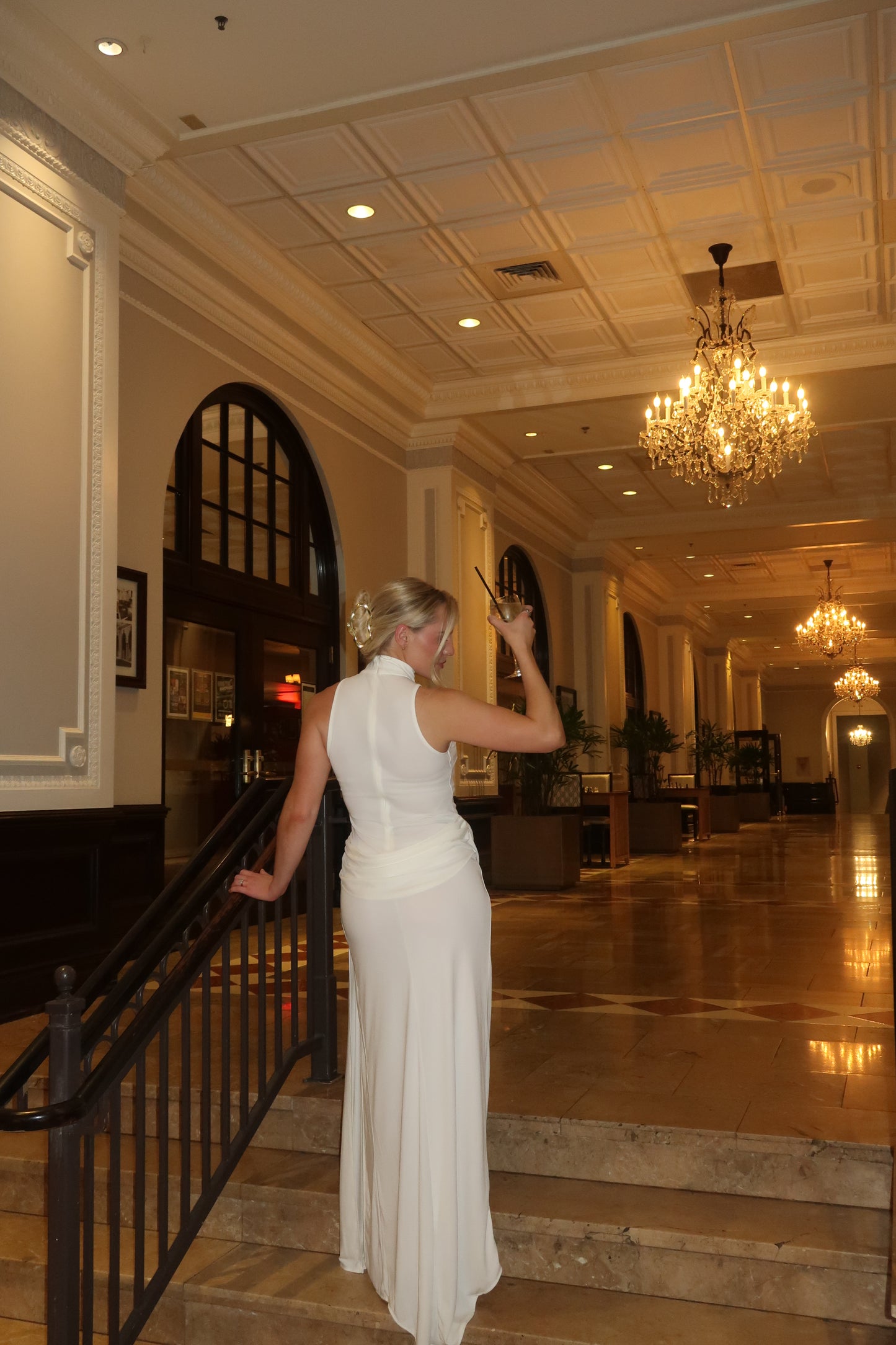 Woman in a white dress standing in a room with decorative lighting and decor.