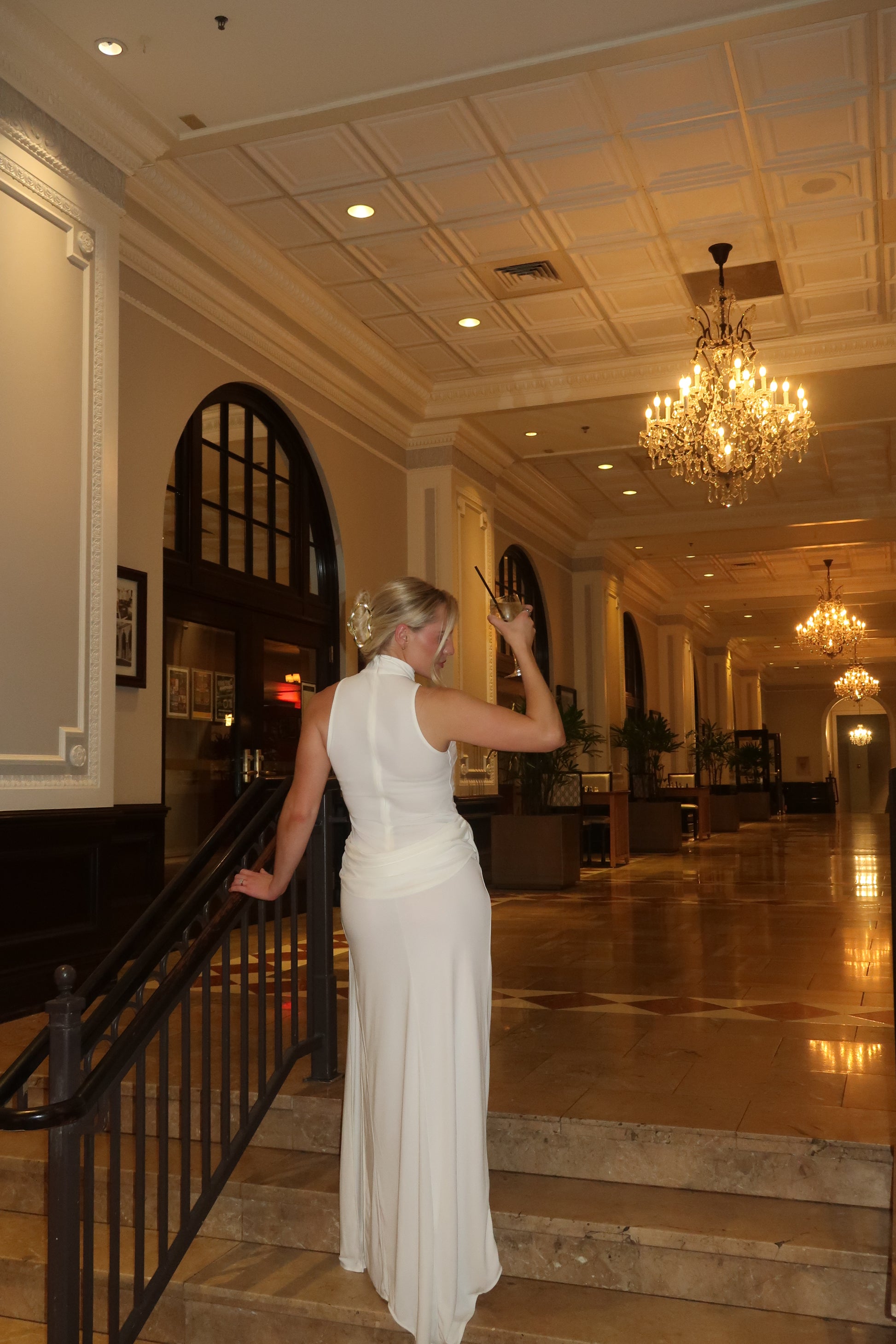 Woman in a white dress standing in a room with decorative lighting and decor.