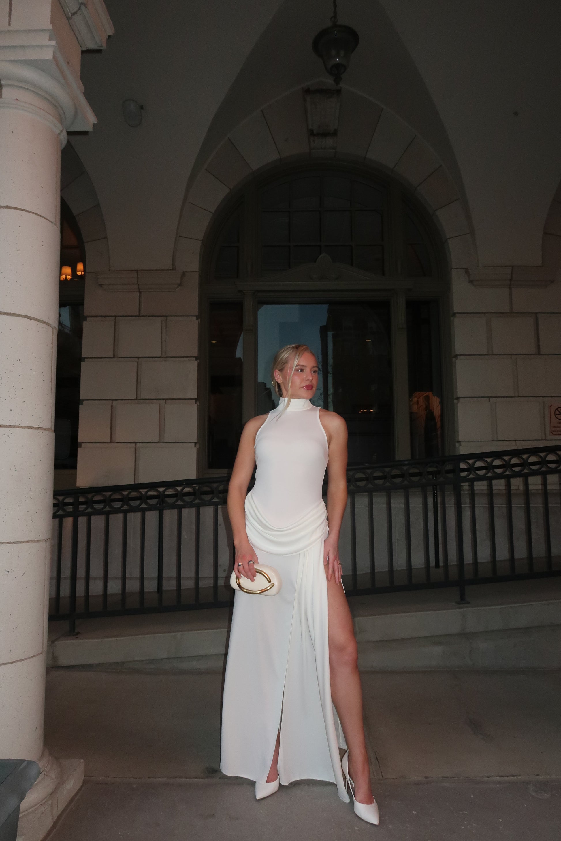 Woman in a white dress standing on a staircase in an indoor setting