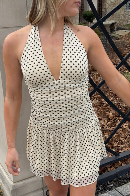 Woman wearing a polka dot dress standing outdoors.