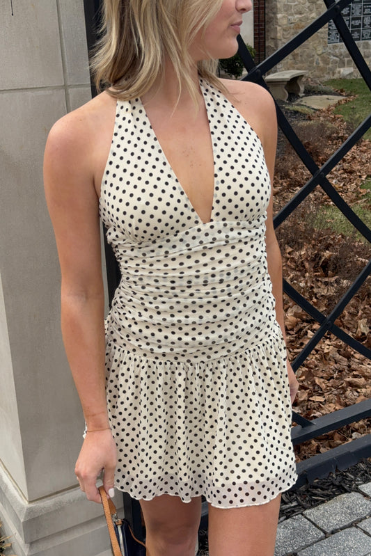 Woman wearing a polka dot dress standing outdoors.