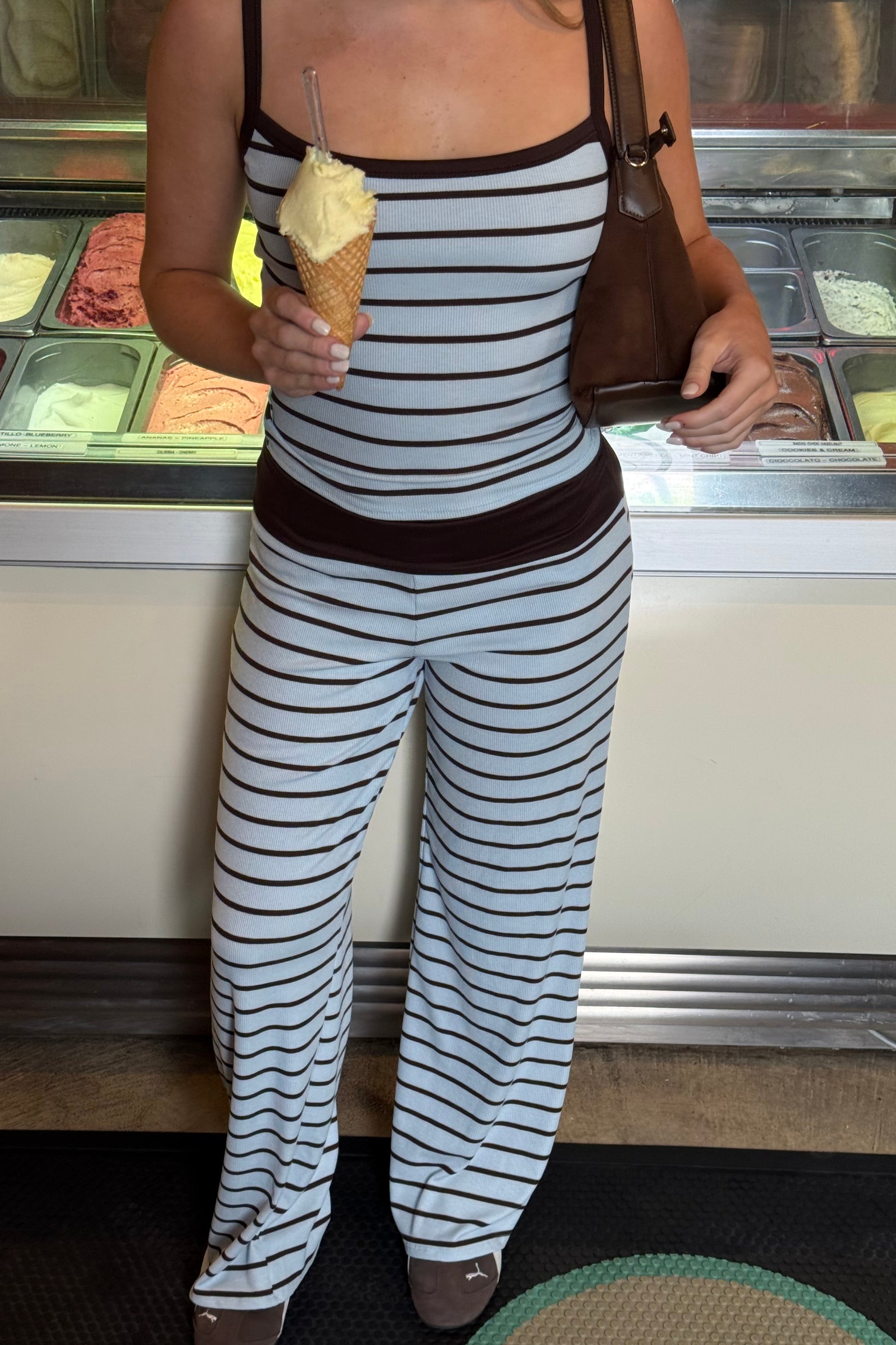 Person wearing a striped outfit holding ice cream in front of an ice cream machine.
