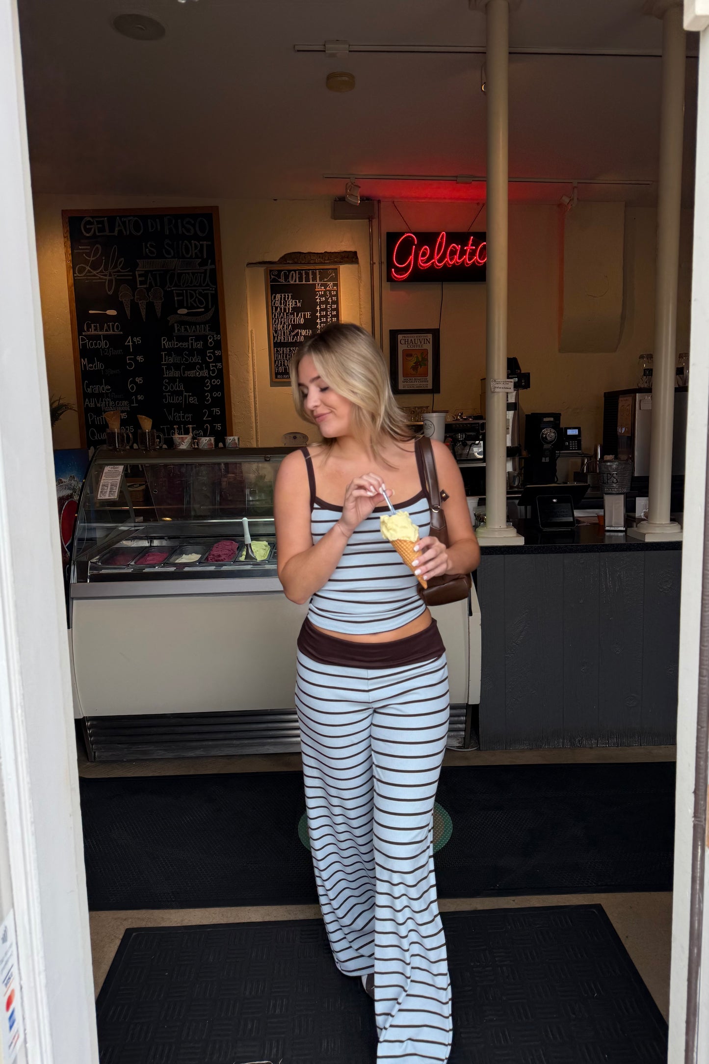 Woman holding a drink in a casual setting with a neon sign in the background