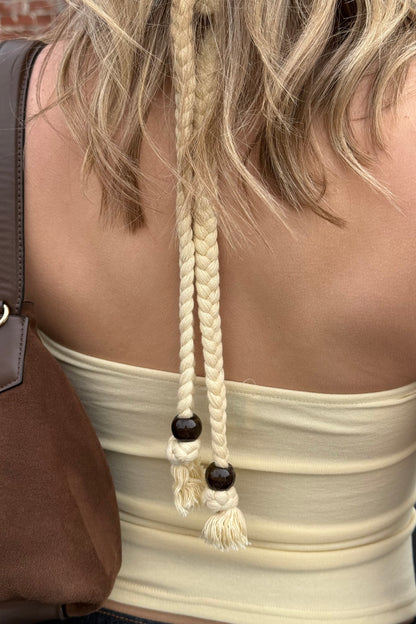 Close-up of a person wearing a beige top with braided hair ties.