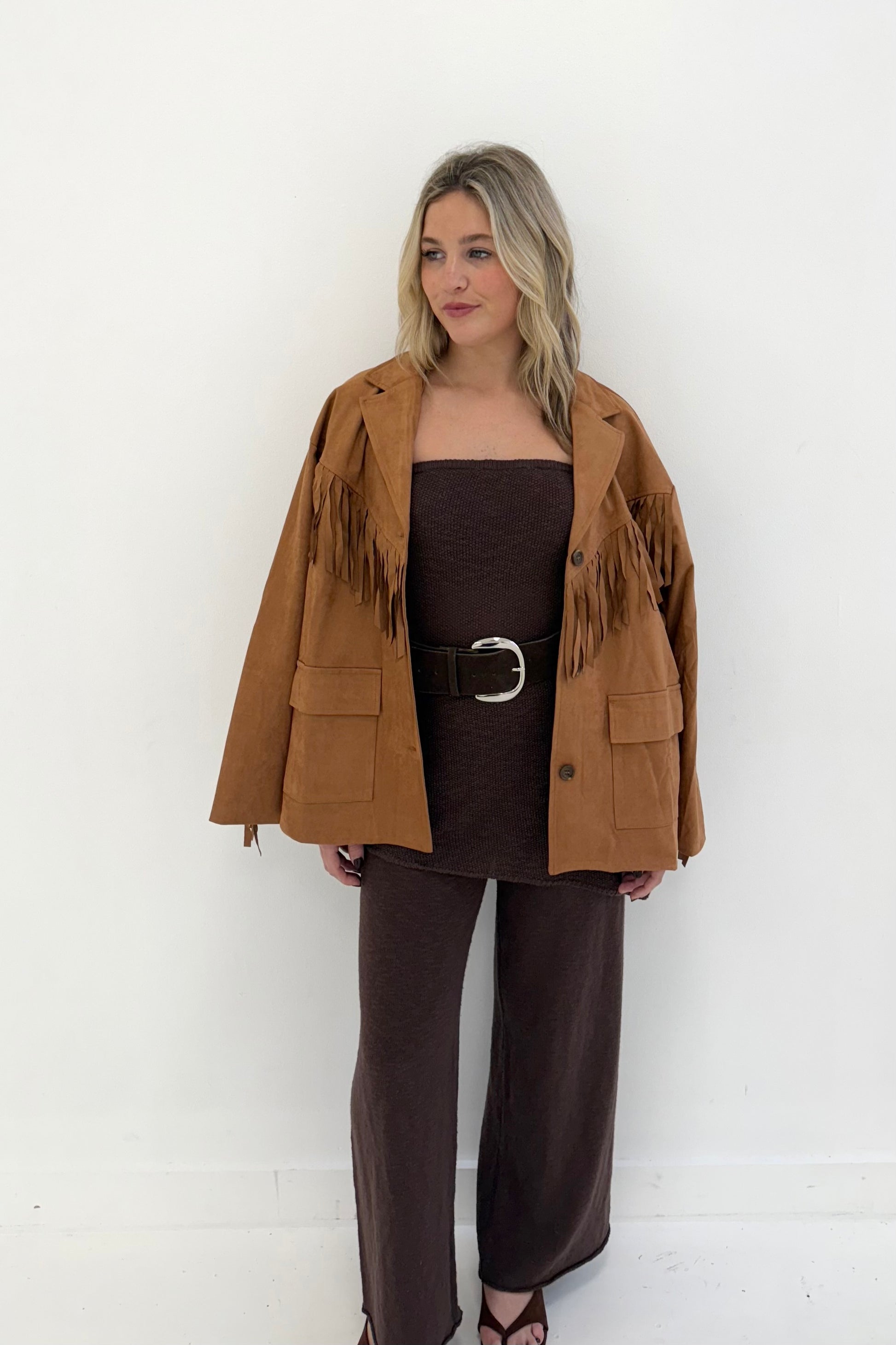 Brown suede fringed jacket styled with a brown outfit, perfect for a trendy, bohemian look.