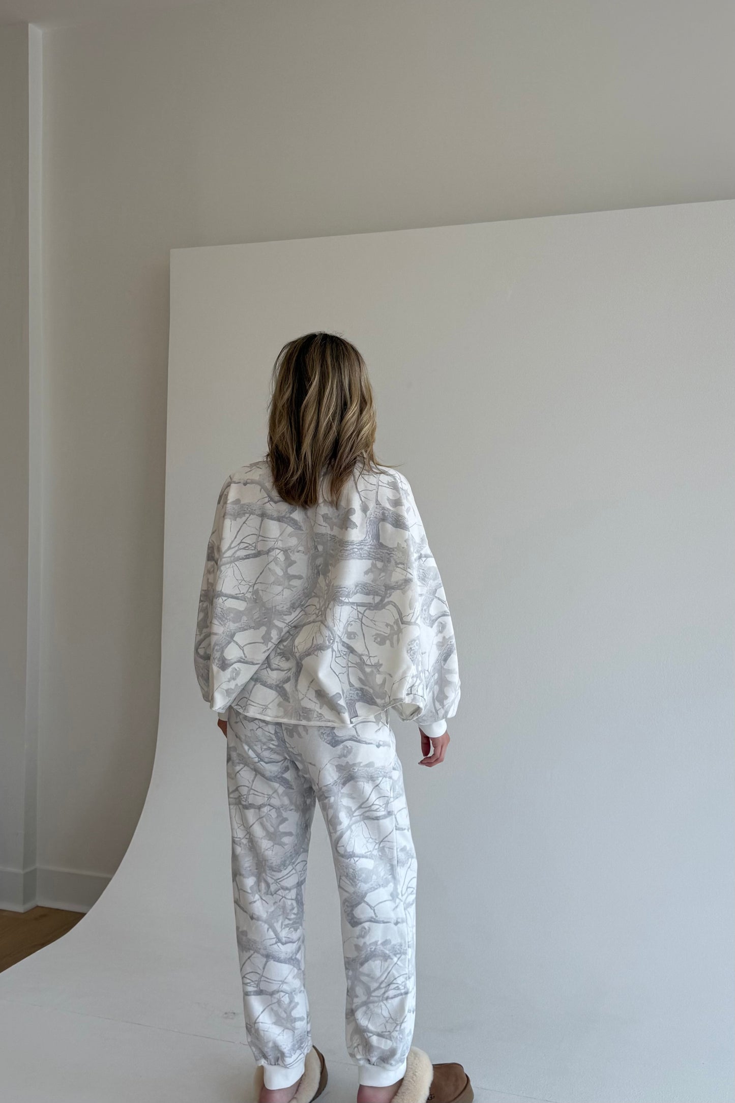 Person wearing a white marble patterned outfit standing against a plain white background