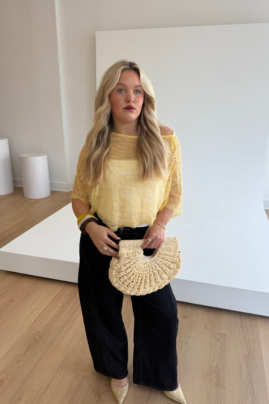 Woman holding a woven handbag indoors with a neutral background