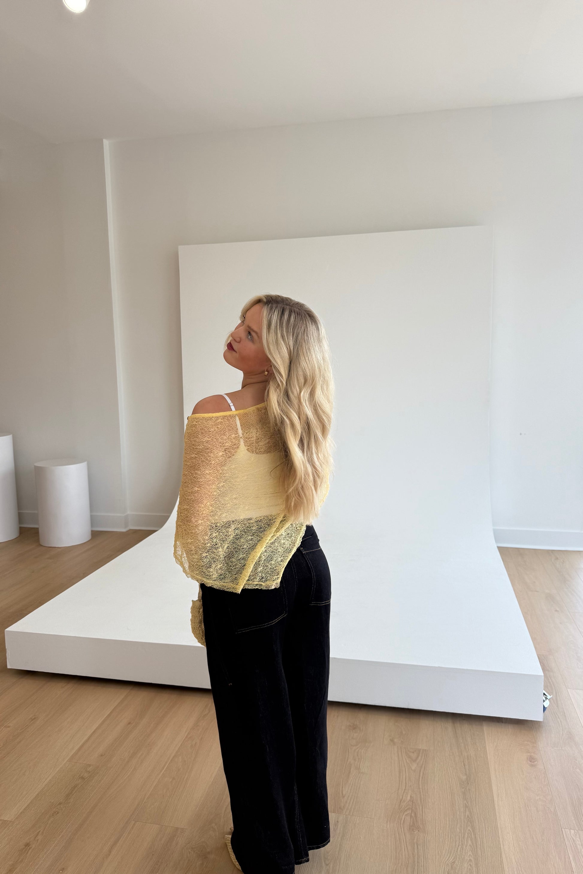 Woman wearing a yellow knitted top in a minimalistic room.