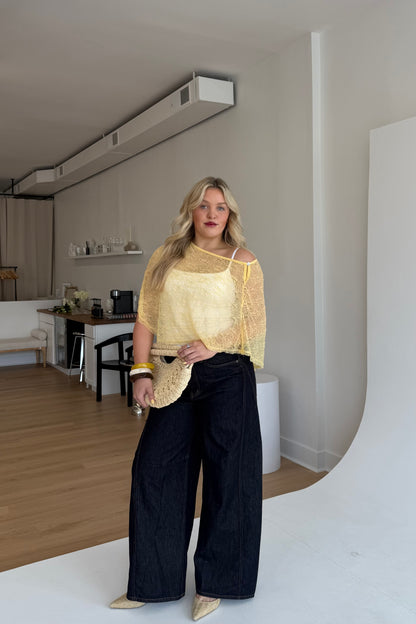 Woman in a yellow top and black pants standing in a modern living room.