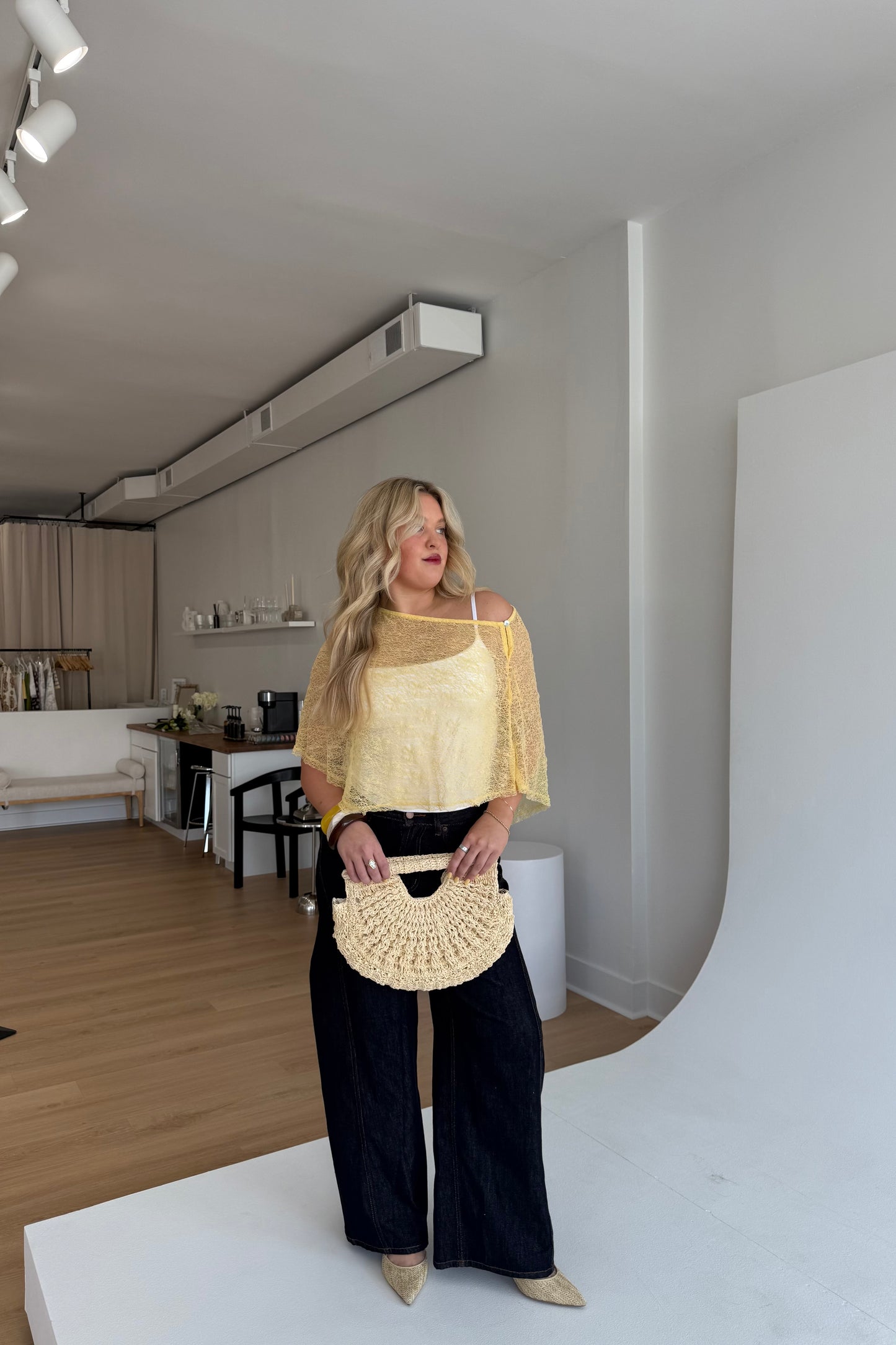 Woman holding a beige handbag in a modern living room.