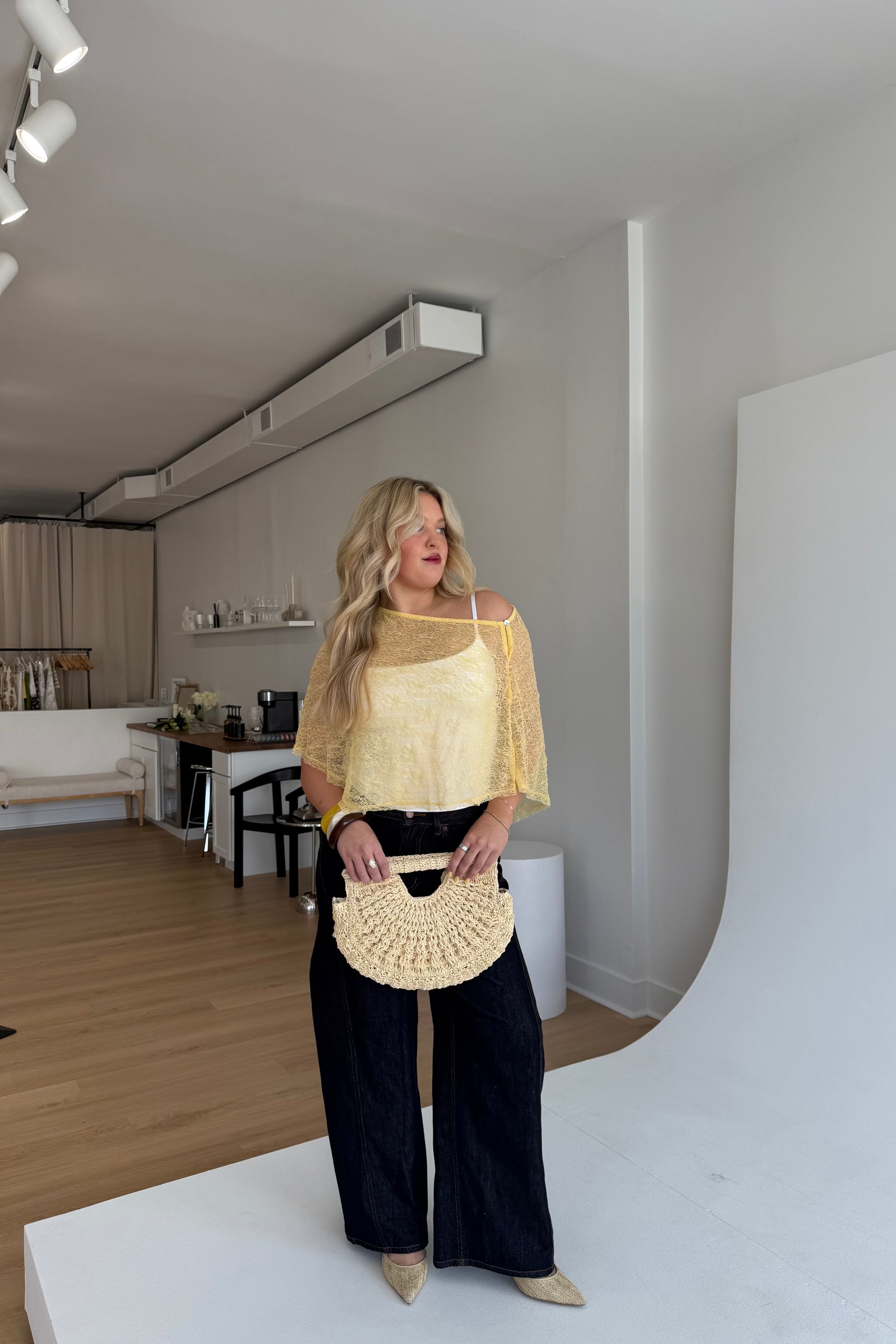 Woman holding a beige handbag in a modern living room.
