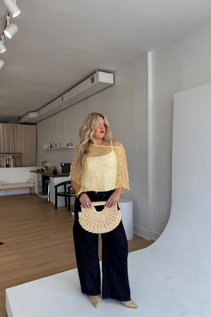 Woman holding a beige handbag in a modern living room.