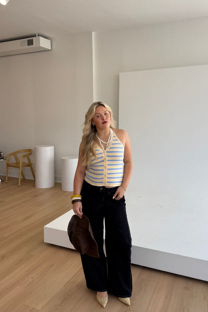 Woman in a striped top and black pants standing in a minimalistic room.
