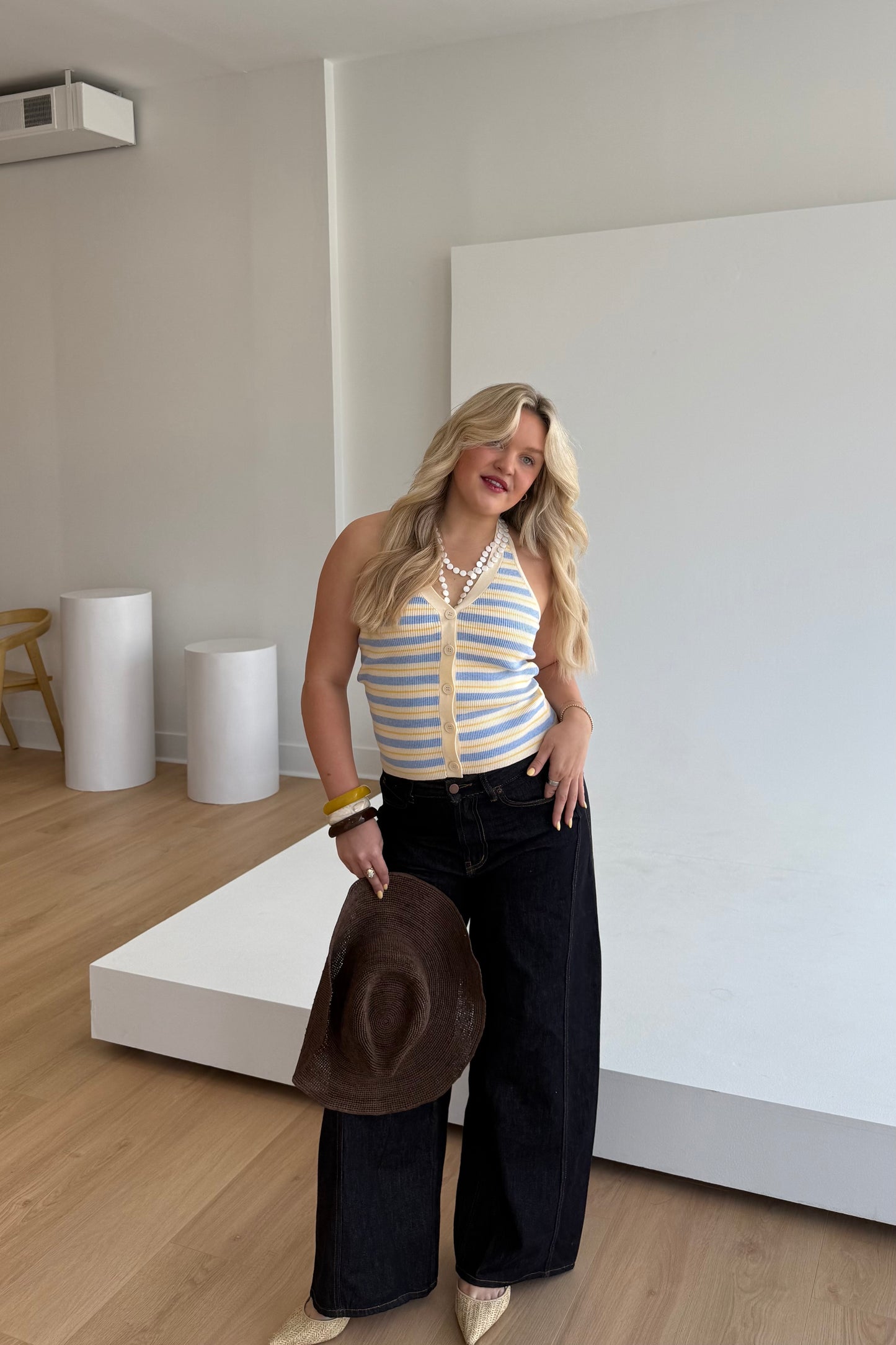 Woman standing in a modern indoor setting holding a hat