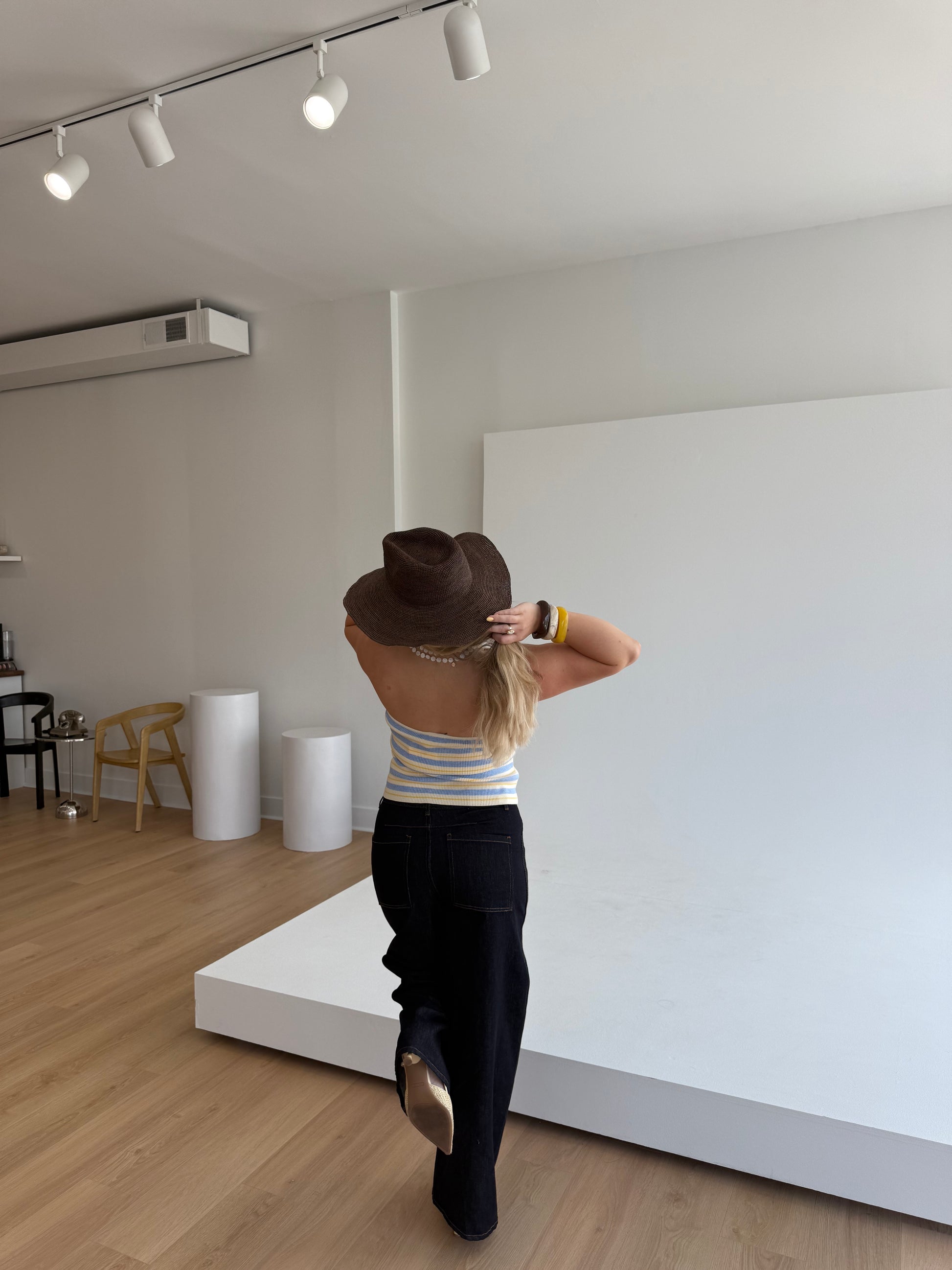 Person standing in a room with a white wall and wooden floor.