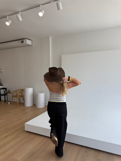 Person standing in a room with a white wall and wooden floor.