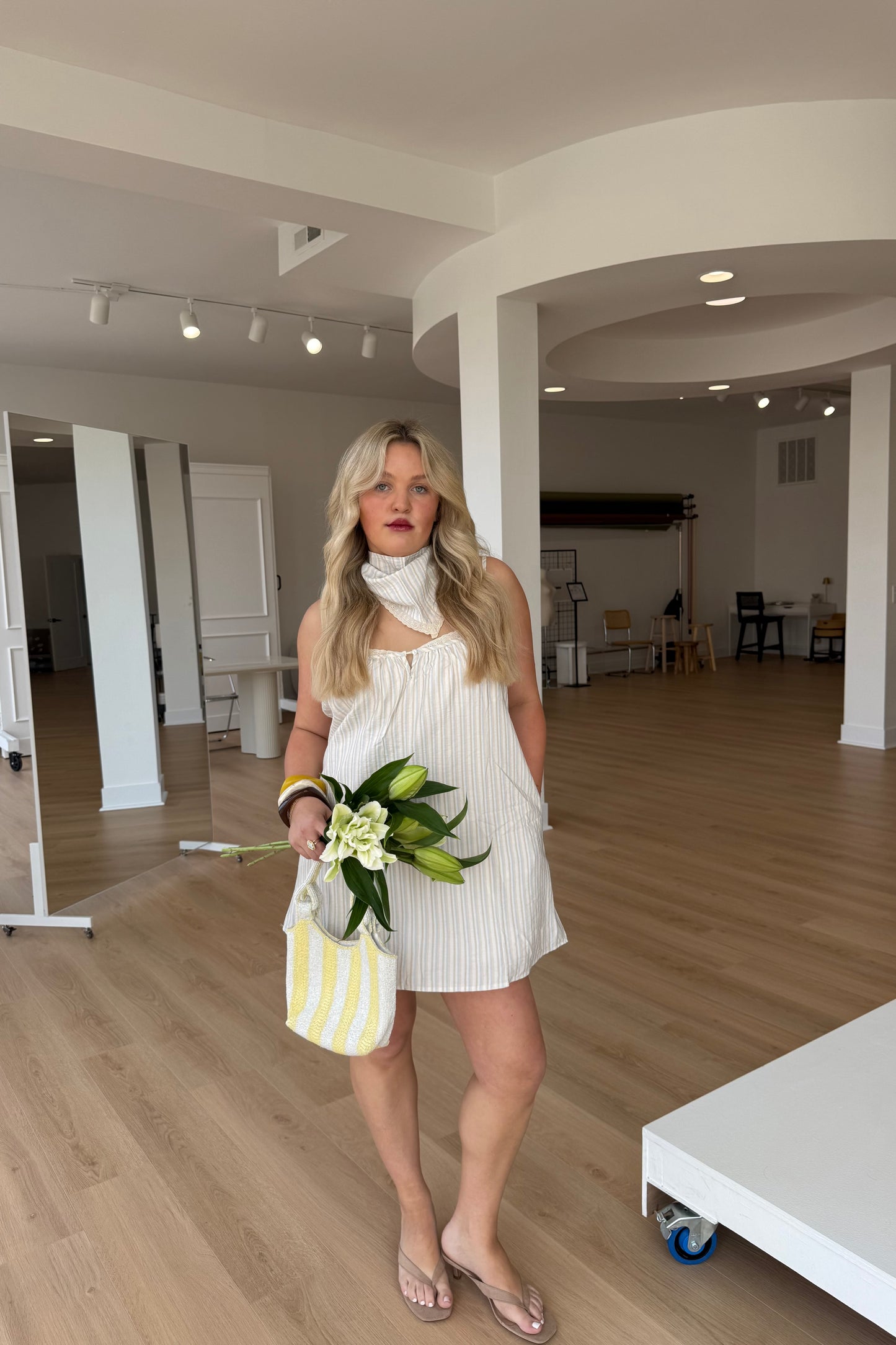 Woman in a white dress holding flowers in a modern indoor setting